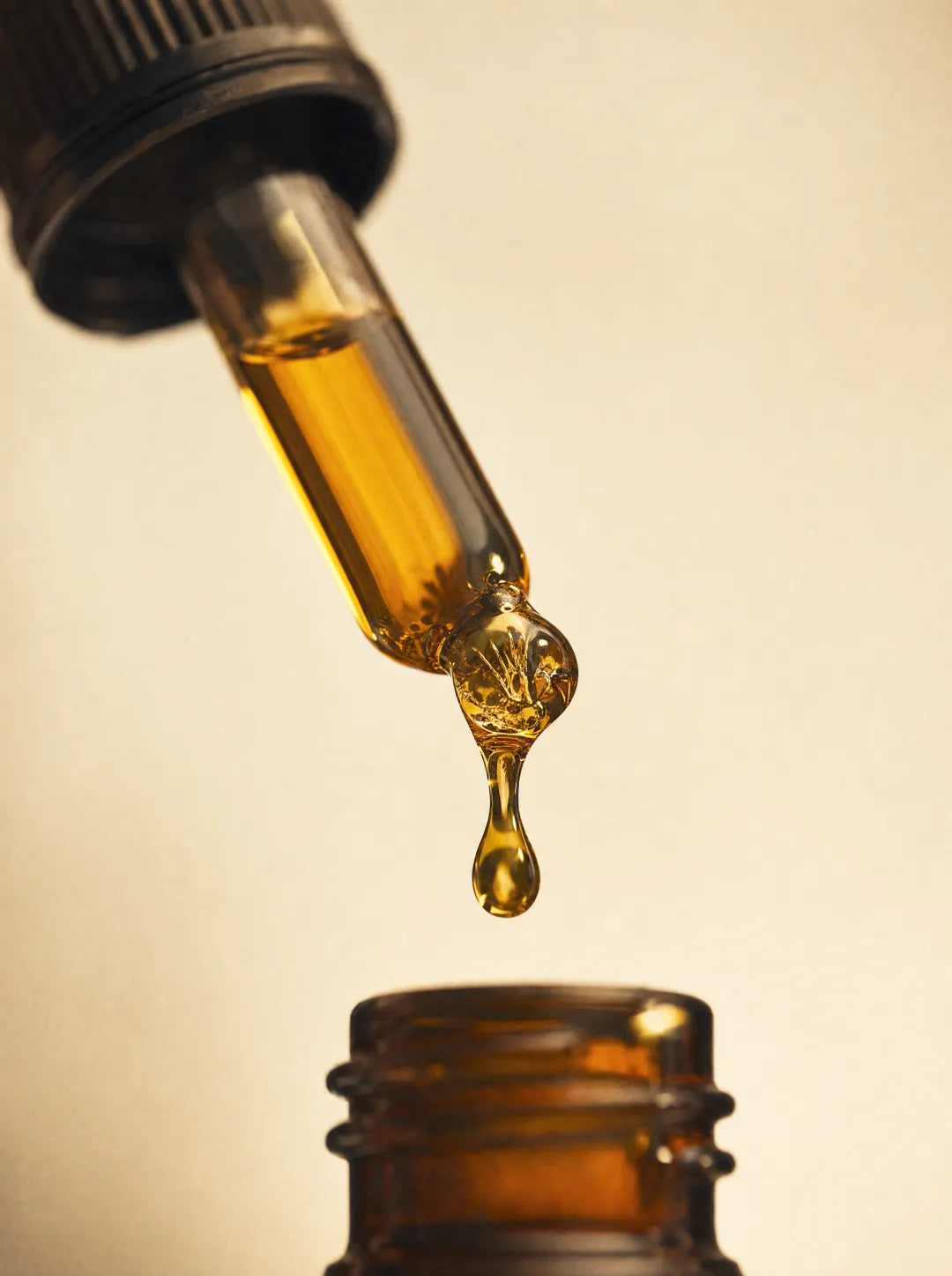 Golden beard oil dripping from an amber glass dropper
